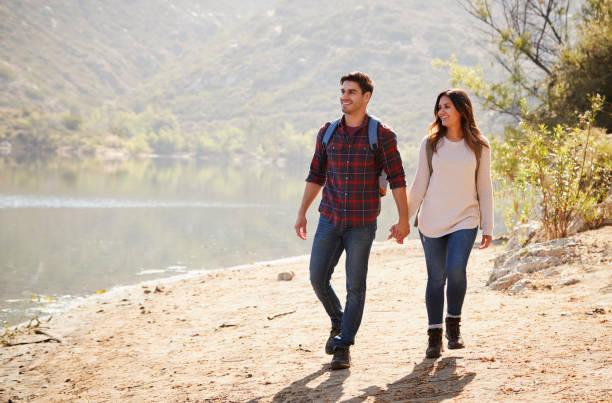 istock Young couple walk holding hands by a mountain lake 1030966130