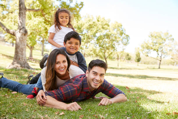 young kids and parents lying in pile on the grass, portrait - family white family with two children cheerful imagens e fotografias de stock