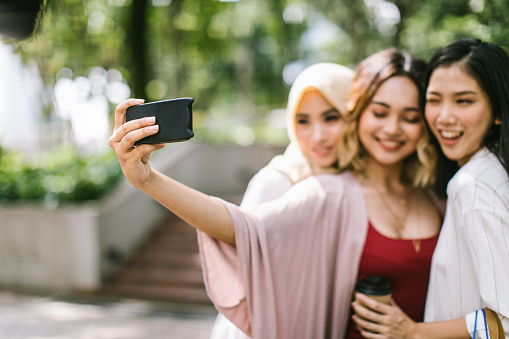 Multi-ethnic group of beautiful women taking a selfie in the park, Kuala Lumpur, Malaysia
