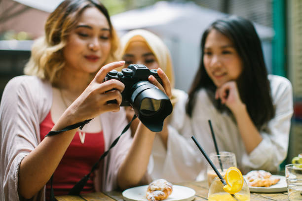 Girlfriends having a great time in the cafe Multi-ethnic group of women having fun using camera in the cafe, Kuala Lumpur, Malaysia muslim photographer stock pictures, royalty-free photos & images