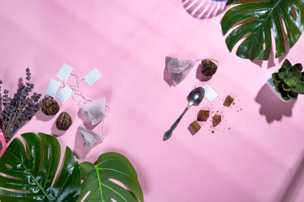 istock frame with green tropical leaf and tea cup, tea bag and sugar on pastel pink background with beautiful deep shadows. Flay lay. 1030982828
