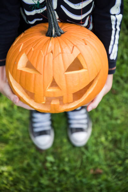 istock Boy in skeleton costume holding pupmkin 1030985548