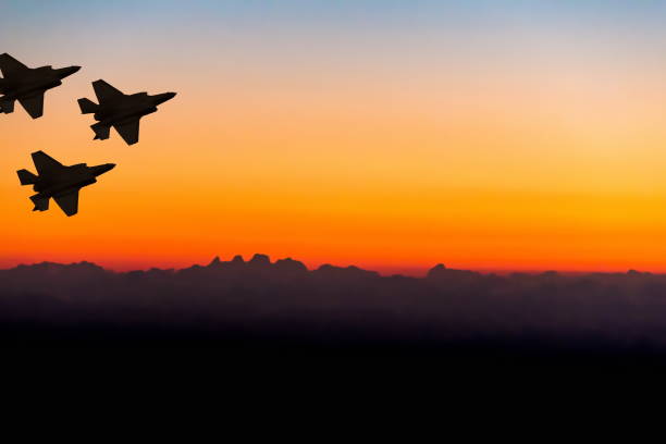 Silhouettes of three super modern fighter-bomber aircraft on sunset sky background stock photo