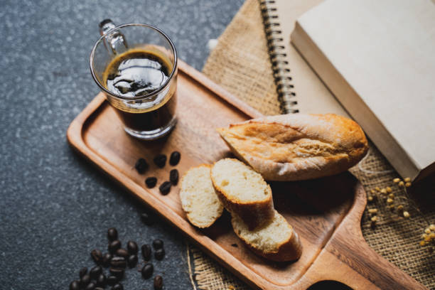istock A coffee, bread, wood plate and book setting on black background 1031001614