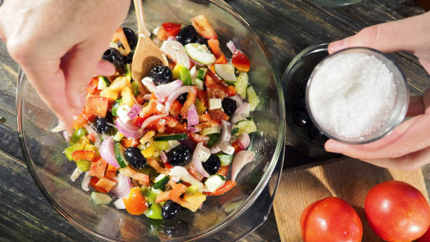 ギリシャのサラダを作る - 塩をふる ストックフォトと画像