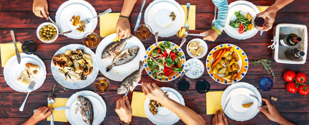 istock Big family dinner in process. Top view vertical image on table with food and hands 1031030598