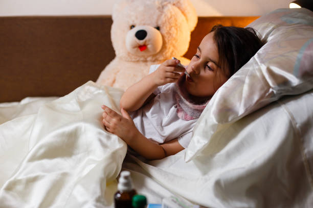 istock Sick girl with a thermometer in mouth lying in bed grumpy face 1031066614