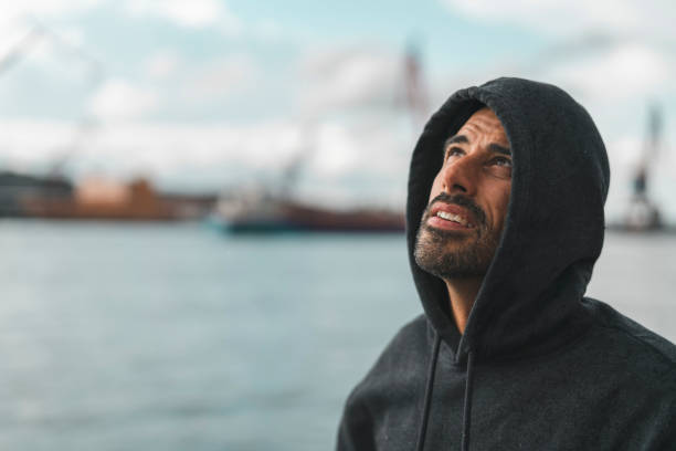 A mature man is resting with a bottle of water in Gothenburg harbor after an outdoor exercise. Shot on a partly cloudy summer day in Sweden.