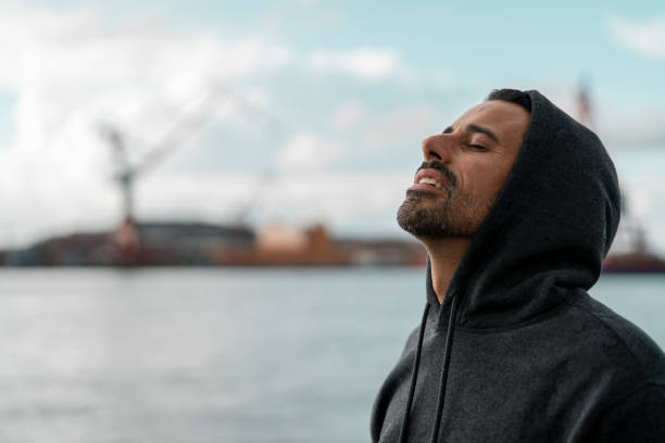 A mature man is resting with a bottle of water in Gothenburg harbor after an outdoor exercise. Shot on a partly cloudy summer day in Sweden.