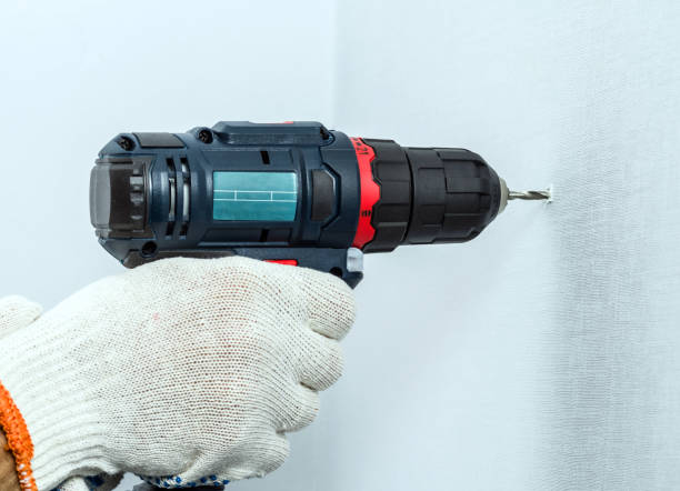 istock Drilling the wall with a cordless drill in protective gloves 1031083280