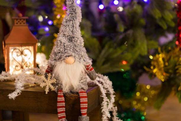 Christmas elf on a wooden bench and red lantern on background