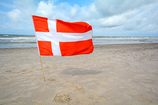 Danish flag in the wind at sand beach near Blavand, Jutland Denmark