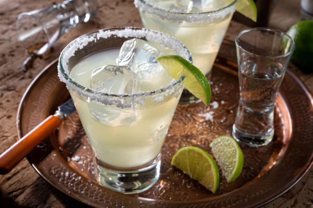 Tequila and Lime Margaritas Delicious tequila and lime margaritas on a copper charger with coarse salt rimmer. margarita stock pictures, royalty-free photos & images