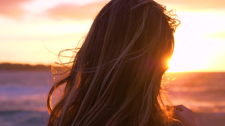 CLOSE UP: Unrecognizable female photographer looks at the sunset over the ocean.