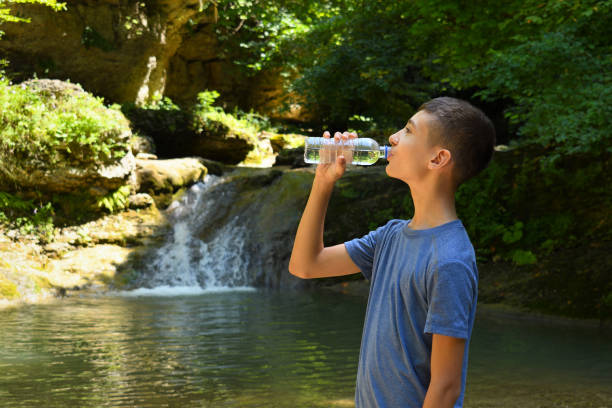 istock Boy drinks water from bottle outdoors 1031113608