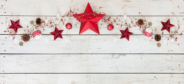 A whimsical Christmas holiday arrangement of stars and ornaments on an old grungy white wood background