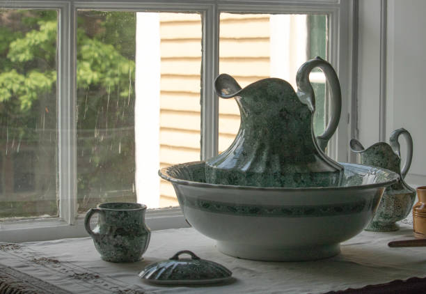Antique pitcher and bowl from 1800s sitting on washstand, romantic vintage Victorian elegance