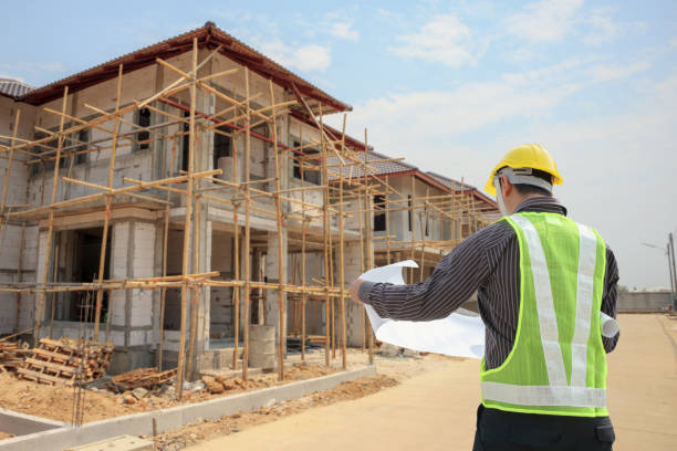 istock Professional engineer architect worker with protective helmet and blueprints paper at house building construction site 1031169772