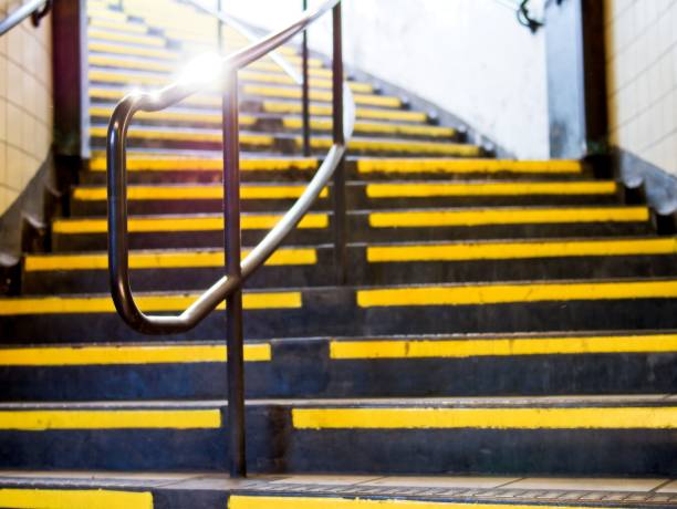 Perspective view of yellow highlighted stairs with silver metal handrail Perspective view of yellow highlighted stairs with silver metal handrail caution step stock pictures, royalty-free photos & images