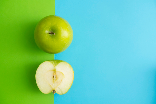green apple on green and blue background in healthy fruit concept. flat lay out,top view