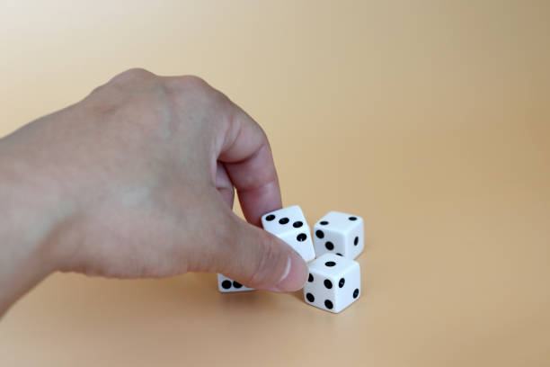 istock Hands trying to pick up the dice on a soft brown background. 1031196422