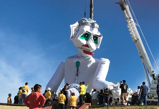 Santa Fe, NM: The puppet known as Zozobra, built by the Santa Fe Kiwanis Club, is being hoisted in place by a crane as onlookers watch. The burning of Zozobra—also known as “Old Man Gloom”—is the centerpiece of the annual Santa Fe Fiesta.