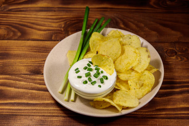 istock Crispy potato chips with green onion and sour cream on wooden table 1031230132
