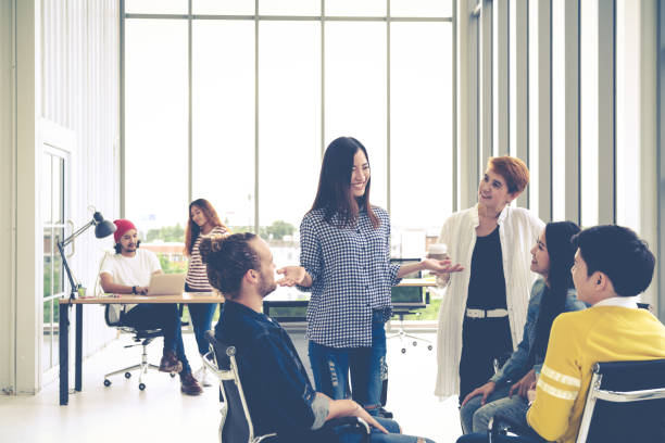 istock Group of young multiethnic creative team engaged brainstorm in small meeting while standing, sitting and talking together in modern office. Casual business with teamwork community discussion concept. 1031232642