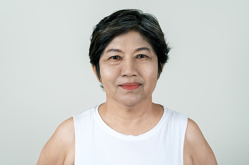 Portrait of attractive senior asian old woman smiling and looking at camera in studio with white isolated background feeling positive granny. Headshot of mature older female or grandma concept.