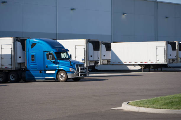istock Big rig semi truck with refrigerated semi trailer standing for loading cargo in warehouse dock with another refrigerator semi trailers 1031238052