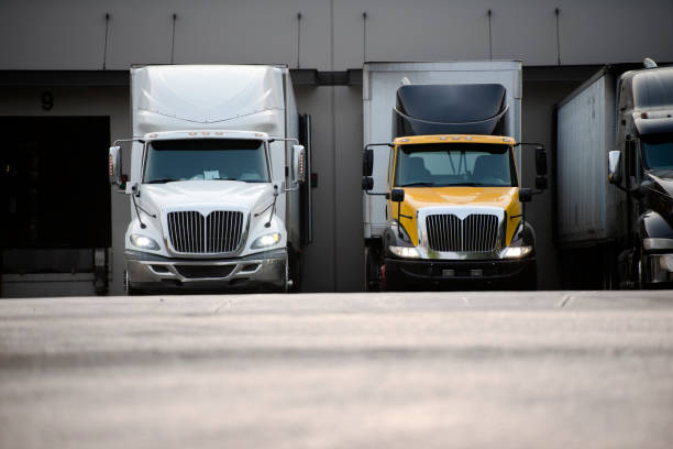 istock Big rig semi trucks with semi trailers standing in warehouse dock for loading commercial cargo 1031238318
