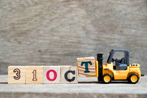 istock Toy forklift hold block T to complete word 31 oct on wood background (Concept for calendar date in month October, Halloween) 1031240734