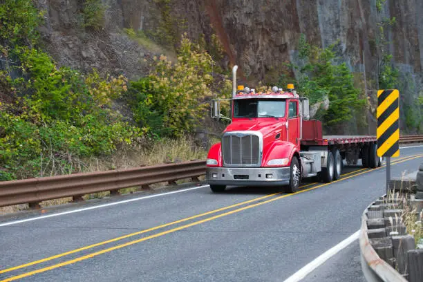 Powerful professional big rig semi trucks day cab tractors with hood motors are used by owner operators to transport on flat bed trailer all types of industrial goods to all corners of America