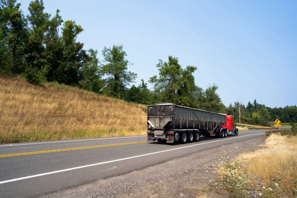 istock Red classic big rig semi truck transporting cargo in long covered bulk trailer 1031243634
