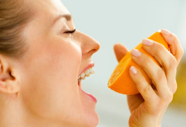 istock Young woman pressing orange juice in mouth 1031248450