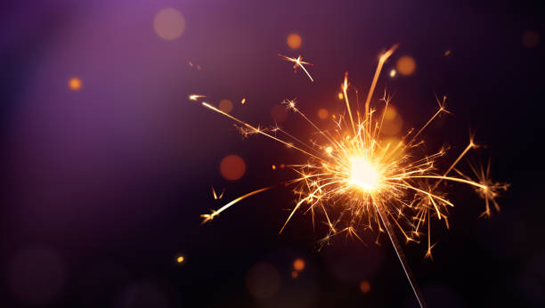 istock Glittering burning sparkler on purple background 1031254936