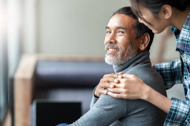 sonriendo a feliz padre asiático más viejo con barba corta elegante tocando la mano de la hija en hombro mirando y hablando con amor y cuidado. relación familiar con el concepto de enlace y atención. - retirement grandfather senior adult child fotografías e imágenes de stock