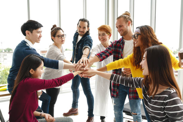 Multiethnic young team stack hands together as trusted unity and teamwork in modern office. Diverse group togetherness collaboration or friends huddle concept. Power of startup business team building. Multiethnic young team stack hands together as trusted unity and teamwork in modern office. Diverse group togetherness collaboration or friends huddle concept. Power of startup business team building. team harmony stock pictures, royalty-free photos & images