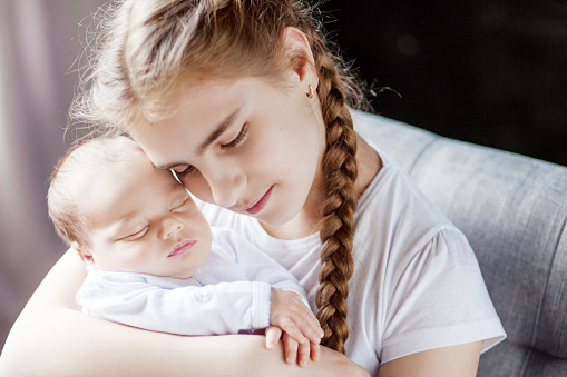 Newborn baby with sister. Girl holding her little brother. Happy sister holding her newborn baby brother. Closeup image