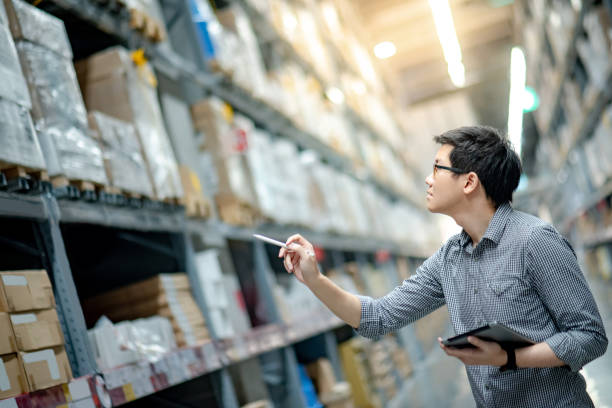 giovane operaio asiatico che fa il punto sul prodotto in scatola di cartone sugli scaffali del magazzino utilizzando tablet e penna digitali. concetto di conteggio dell'inventario fisico - warehouse freight transportation checklist industry foto e immagini stock