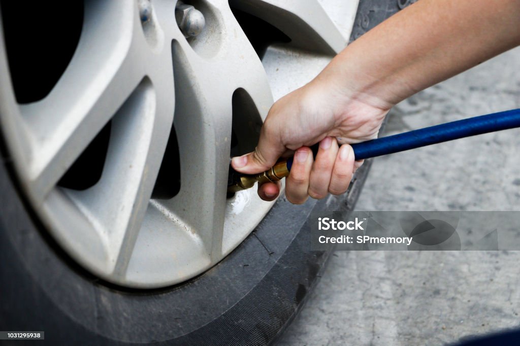 inflating tire and checking air pressure in service station.Filling air into a car tire at service center Tire - Vehicle Part Stock Photo