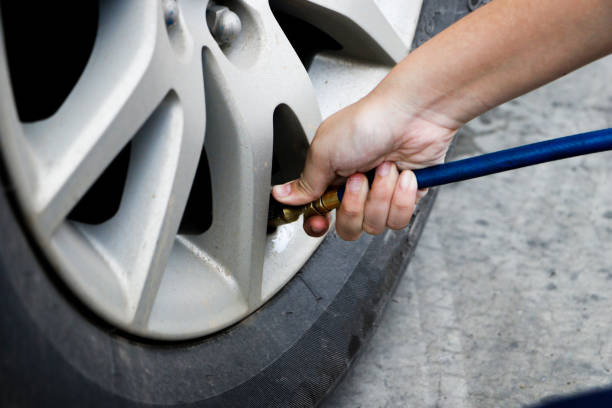 inflating tire and checking air pressure in service station.Filling air into a car tire at service center stock photo