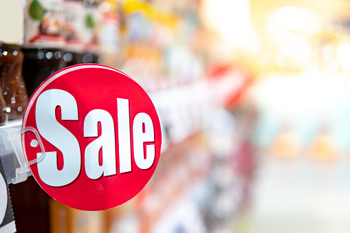 Red sale label on product shelf in supermarket with blurred food aisle in the background. shopping lifestyle in grocery store concept