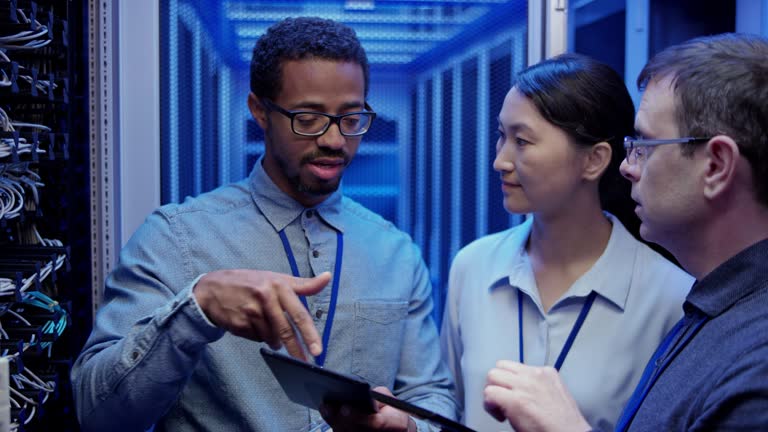 Three colleagues standing in the server room and troubleshooting the reported problem on one of the servers