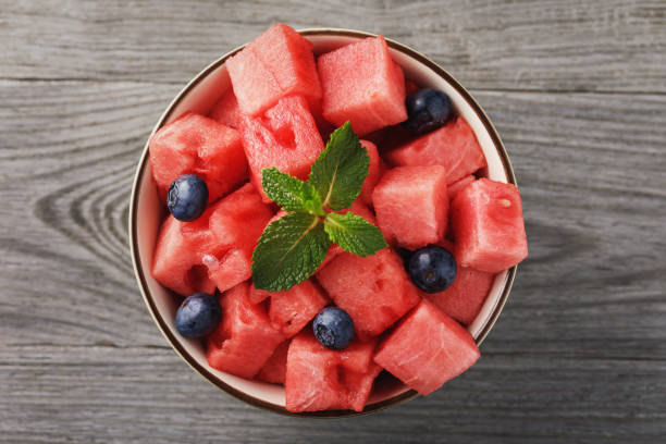 istock Cut watermelon pieces with blueberry berries on a wooden table, top view 1031299182