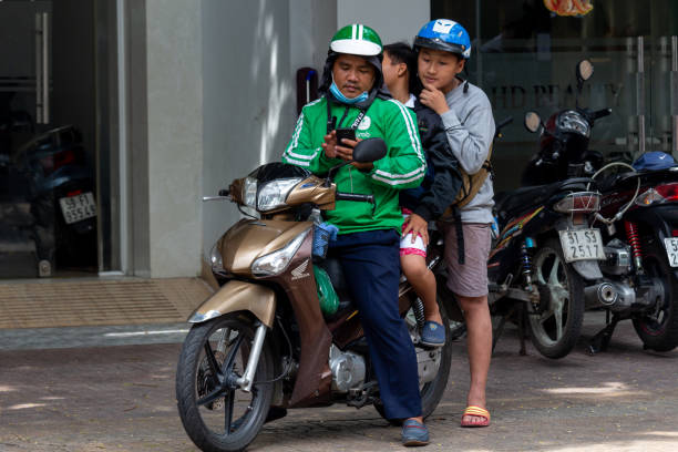 Grab motorbike driver Vietnam Ho Chi Minh City, Vietnam- May 12, 2018: Grab motorbike driver transporting two passengers in Saigon vietnamese man taxi motorbike driver stock pictures, royalty-free photos & images