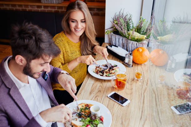 ein fröhliches junges paar, für das frühstück in einem café vor der arbeit - eierkuchen speise stock-fotos und bilder