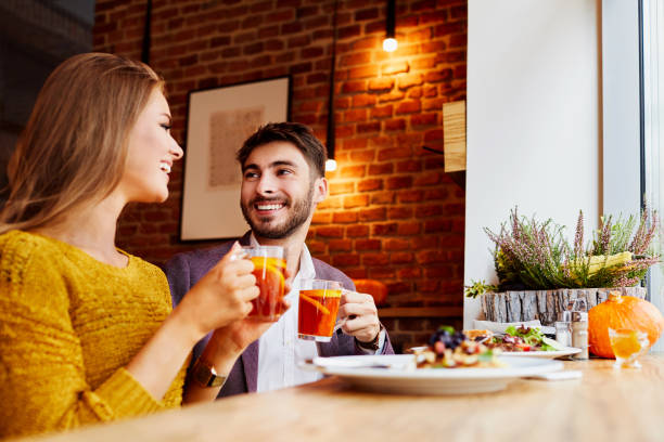 istock Cute cheerful young couple eating together and drinking tea while sitting in a cafeteria 1031313238