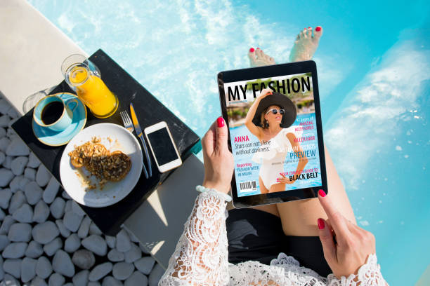 donna che si rilassa a bordo piscina e legge l'emagazina su tablet a colazione. tutti i contenuti sono insorti. - vacations holiday internet summer foto e immagini stock