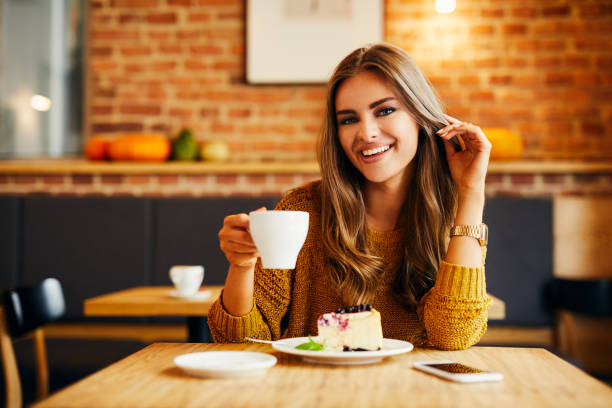 istock Attractive young woman smiling and looking at camera while having cake and coffee in a cafe 1031313574